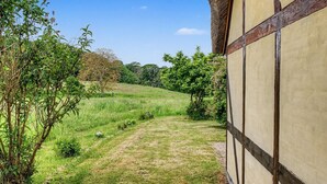 Un sendero rural que lleva a una construcción tradicional con entramado de madera y techo de paja.