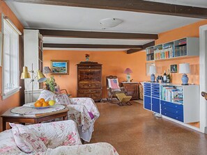 Una sala de estar acogedora con chimenea, una estantería y un comedor con una mesa dispuesta para dos.
