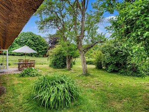 A patio area with a table and chairs, surrounded by lush greenery and trees. - "Sida" - 1.3km from the sea by Interhome (Tranekær)