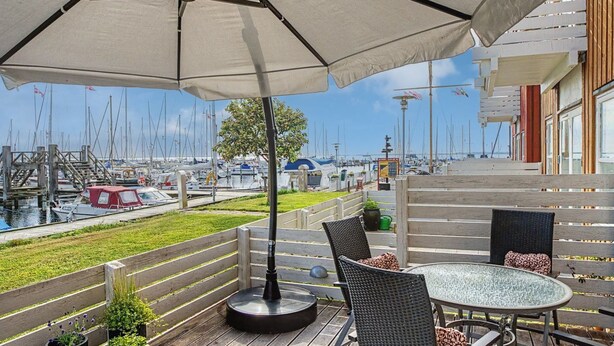 Un espace extérieur abrité, aménagé avec des sièges, et offrant une vue sur un port de plaisance.