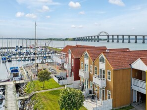 Ein Yachthafen mit Booten, eine Brücke im Hintergrund und Holzhäuser mit Balkonen.