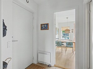 A hallway leading to a dining area with chairs and a table, a radiator, and a door with a bag hanging on it. - "Riku" - 15m from the sea by Interhome (Rudkøbing)
