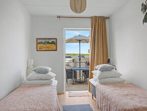 A room with two beds, a painting, a table with chairs, and a view of the outdoors. - "Riku" - 15m from the sea by Interhome (Rudkøbing)