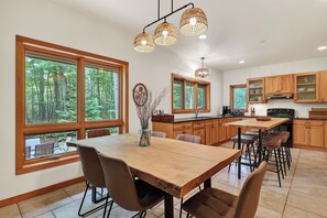 A modern kitchen with large windows, wooden cabinets, and a central island. - Jacksonport Woodland Hearth Retreat - Near Lake Michigan (Sturgeon Bay)