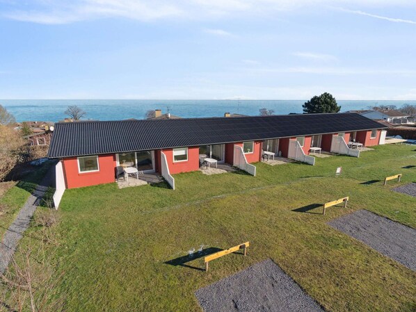 Eine Reihe roter Gebäude mit schwarzen Dächern, jedes mit einer Terrasse und Blick auf das Meer.