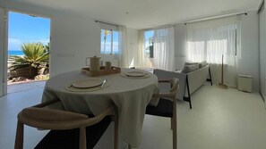 Ein moderner Essbereich mit einem runden Tisch, Stühlen und Meerblick.