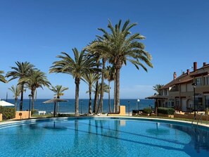 Ein Pool mit Palmen und Blick aufs Meer.
