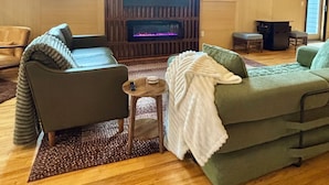 Un salon avec une cheminée, deux canapés, une table basse et un téléviseur.