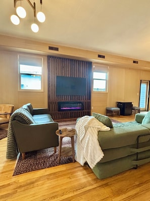A living room with a fireplace, two sofas, a coffee table, and a TV.