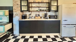Une cuisine avec des meubles de couleur sombre, un réfrigérateur blanc, un four à micro-ondes et une machine à café.