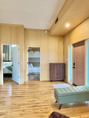 A spacious room with wooden flooring, a large window, and a bed with a view.