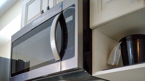 Eine Küche mit Mikrowelle aus Edelstahl, einer Kaffeemaschine und einem Spülbecken.