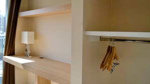 Ein Zimmer mit einem Holzboden, einer Hängelampe und einem Kleiderständer mit Kleiderbügeln.