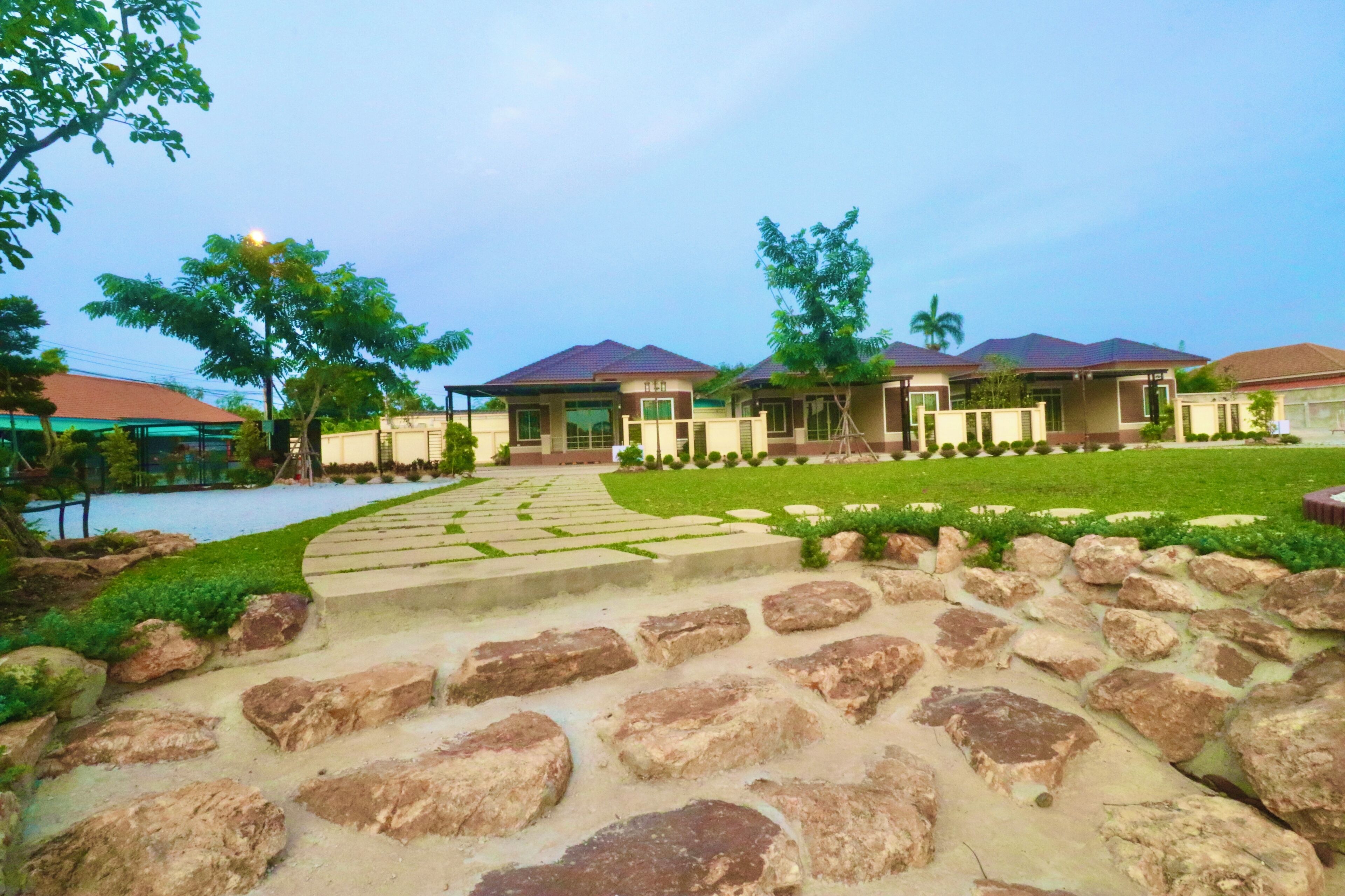 A hotel with multiple buildings, a stone pathway, and a well-maintained lawn.