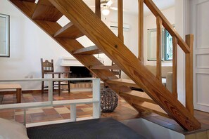 Un escalier en bois avec une rampe, un coin repas avec une table et des chaises, et un tapis à motifs.