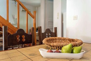 A dining area with a wooden chair, a woven basket, and a white tray with fruits. - Traditional sea front villa, close to reasturants & cafes
With garden & sea view (Kalamata)