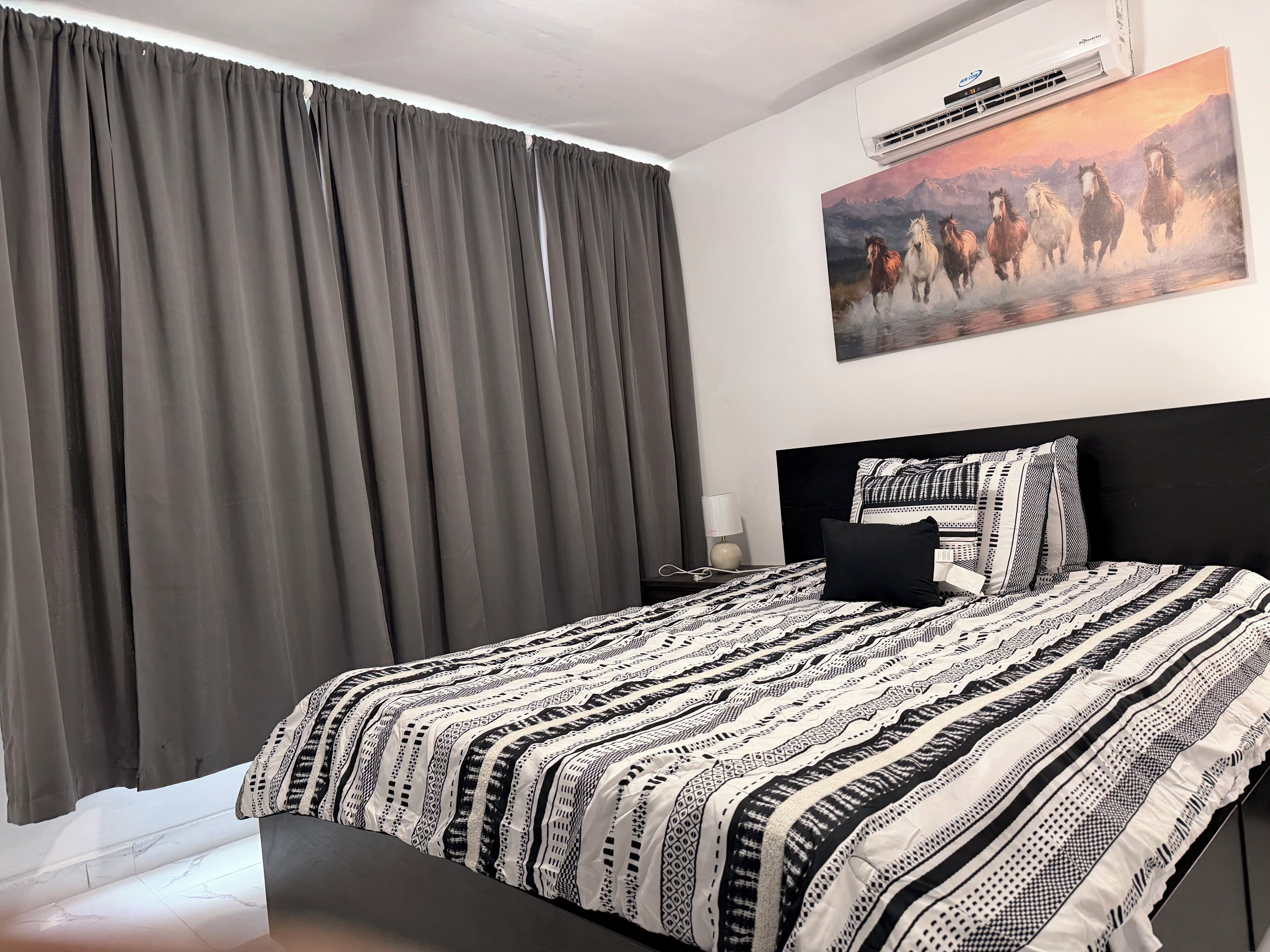 Ein Schlafzimmer mit Bett, Vorhängen, einem Gemälde und einem Nachttisch.