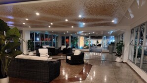A spacious lobby with wicker furniture, large windows, and a polished floor. - My Paradise: Tropical, 3-star, beach, sand—everything at your fingertips (Carolina Puerto Rico)