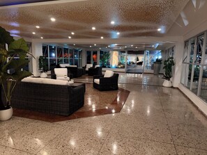 Eine geräumige Lobby mit Korbmöbeln, großen Fenstern und einem glänzenden Boden.