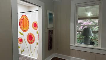 A room with a window, a door with a floral curtain, and a rug on the floor.