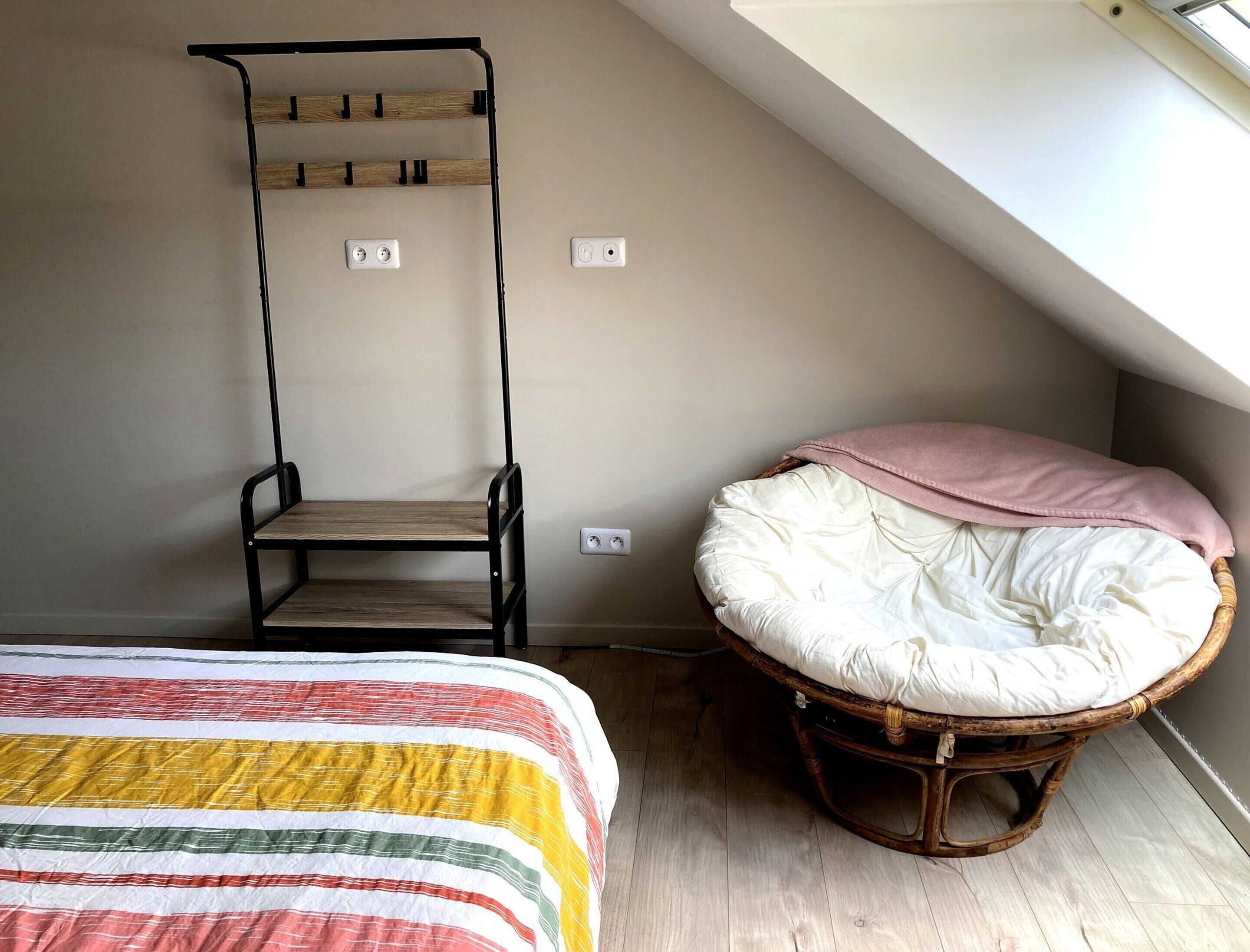 A loft bedroom with a bunk bed, a rattan chair, and a slanted ceiling.