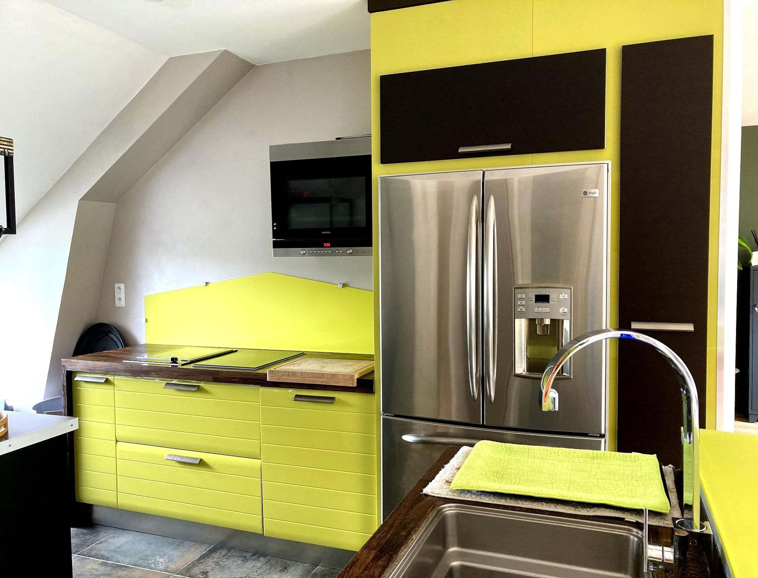 Una cocina con un refrigerador de acero inoxidable, un microondas y un armario amarillo.