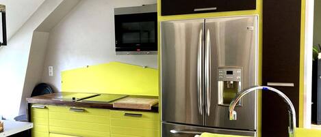 Una cocina con un refrigerador de acero inoxidable, un microondas y un armario amarillo.