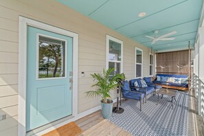 A covered porch with a light blue door, a potted plant, blue furniture, and a patterned rug. - Bayou Breeze  - Pool + Waterfront Views + 8 Minutes to Downtown Pensacola (Pensacola)