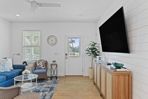 A living room with a sofa, armchair, coffee table, and a TV mounted on the wall. - Bayou Breeze  - Pool + Waterfront Views + 8 Minutes to Downtown Pensacola (Pensacola)
