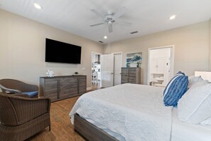A bedroom with a bed, a television, a ceiling fan, and a view into the adjacent room. - Bayou Breeze  - Pool + Waterfront Views + 8 Minutes to Downtown Pensacola (Pensacola)