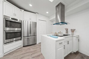 A modern kitchen with white cabinetry, stainless steel appliances, a central island, and a skylight. - Bright and Peaceful Modern Home - Sleeps 5 (Sanford)