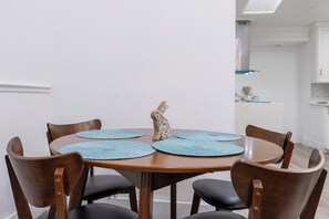 A dining table with four chairs, a decorative animal sculpture, and blue placemats. - Bright and Peaceful Modern Home - Sleeps 5 (Sanford)