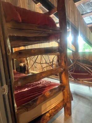 A bunk bed with a wooden frame and a red blanket.