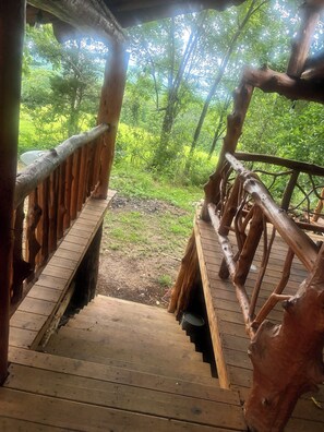 A wooden staircase leading to an outdoor area with a view of a forest.