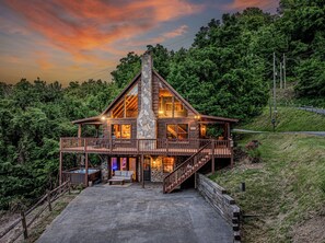 Eine Blockhütte mit einem Steinkamin, einer Terrasse und einem Whirlpool.
