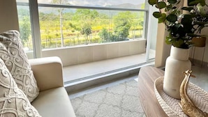 Un salon moderne avec une grande fenêtre, un canapé, une table basse et une plante en pot.