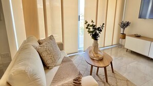 A modern living room with a sofa, a small round table, and a hanging light fixture.