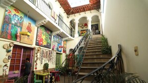 Una escalera estrecha con barandilla de metal que conduce a un balcón en un segundo piso con techo de tejas.