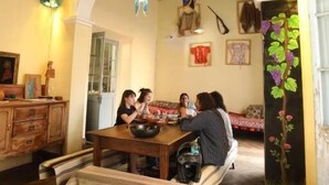 Un comedor con mesa de madera, bancos y un espejo grande.