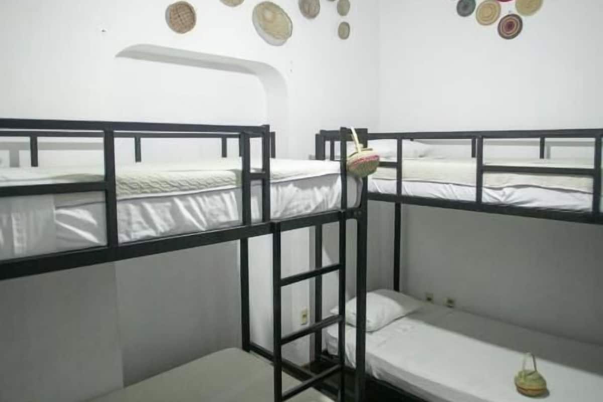Dormitorio con literas, una escalera, una lámpara colgante y un muro decorado con diseños circulares.