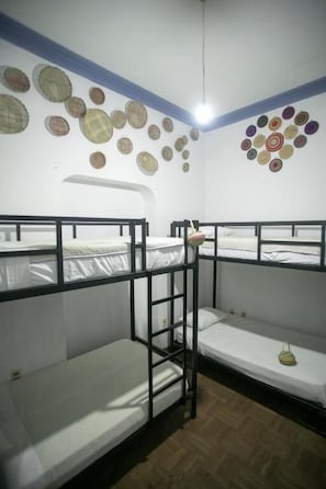 Dormitorio con literas, una escalera, una lámpara colgante y un muro decorado con diseños circulares.