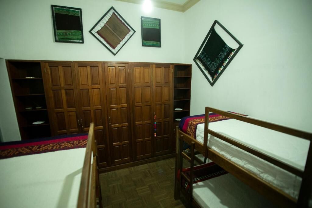 Une chambre avec un lit superposé, une armoire en bois et des étagères fixées au mur.