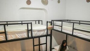 Una habitación con literas, una escalera y una pared decorada con objetos tejidos circulares.