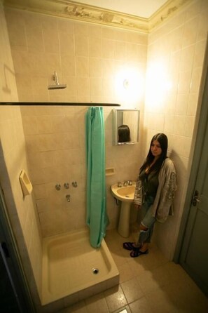 Un baño con ducha, lavabo y espejo.
