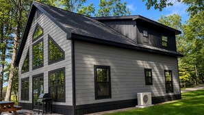 Une maison moderne à deux étages, dotée de grandes fenêtres, d’un patio et d’un système de climatisation.