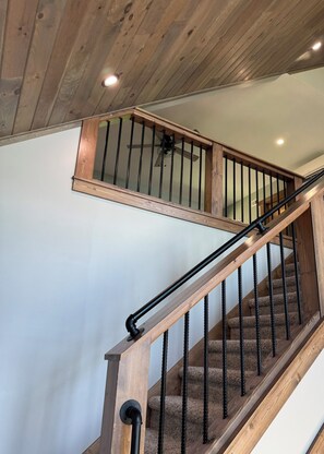 Eine Holztreppe mit schwarzer Handläufe und einem Deckenventilator.