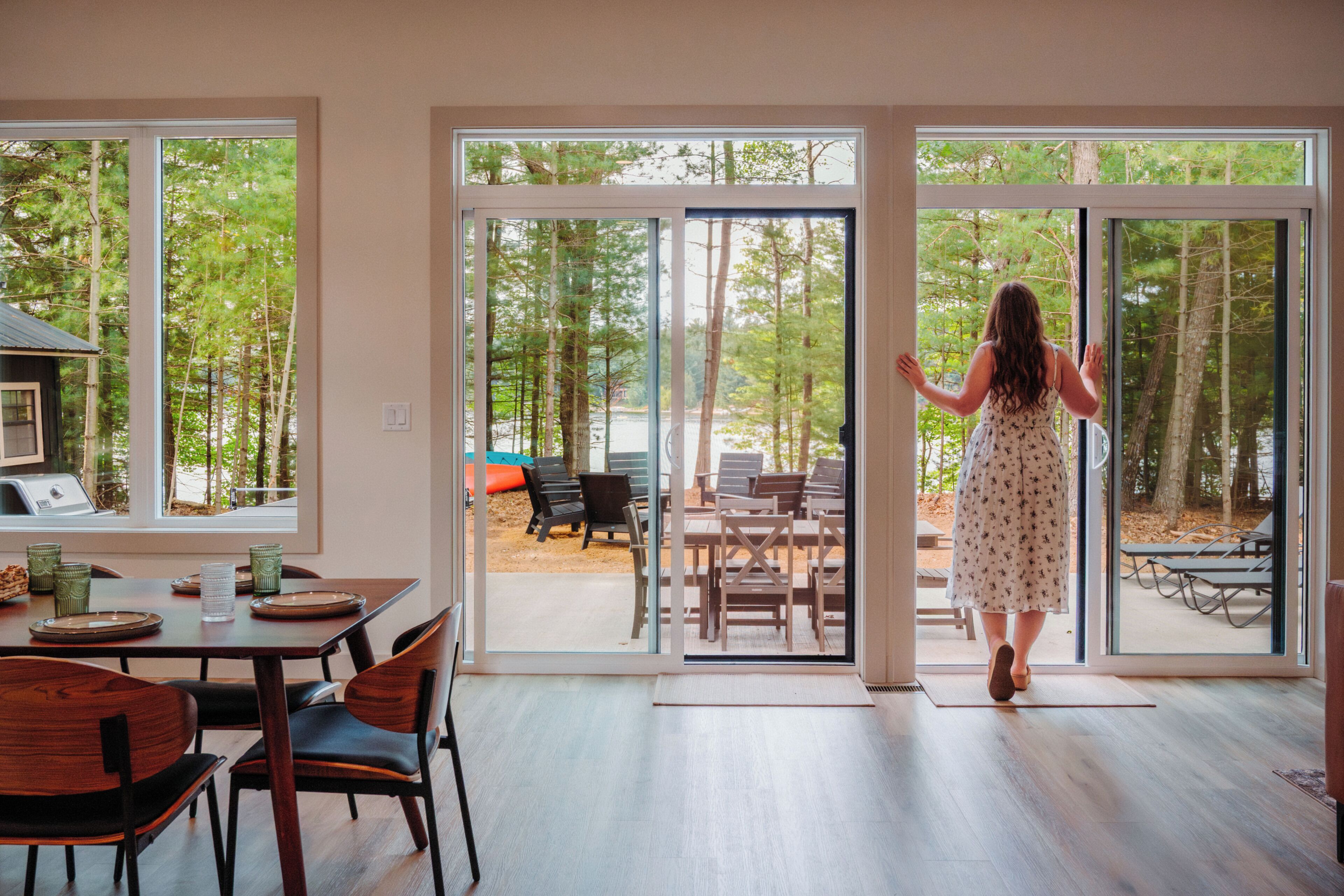 Une pièce dotée d’une grande porte-fenêtre coulissante qui donne sur une terrasse extérieure aménagée avec des meubles en bois.
