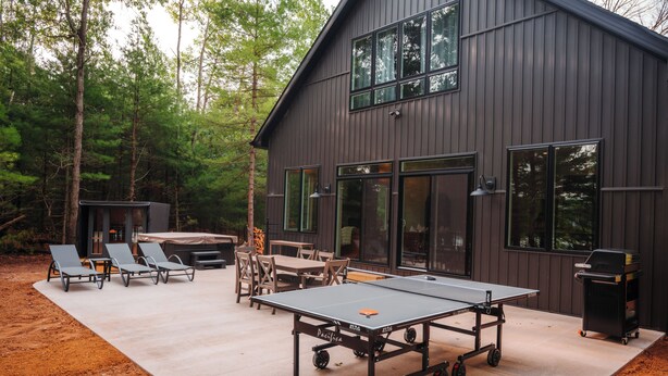 Eine moderne Außenpatio mit Tischtennisplatte, Lounge-Möbeln und Grillbereich.