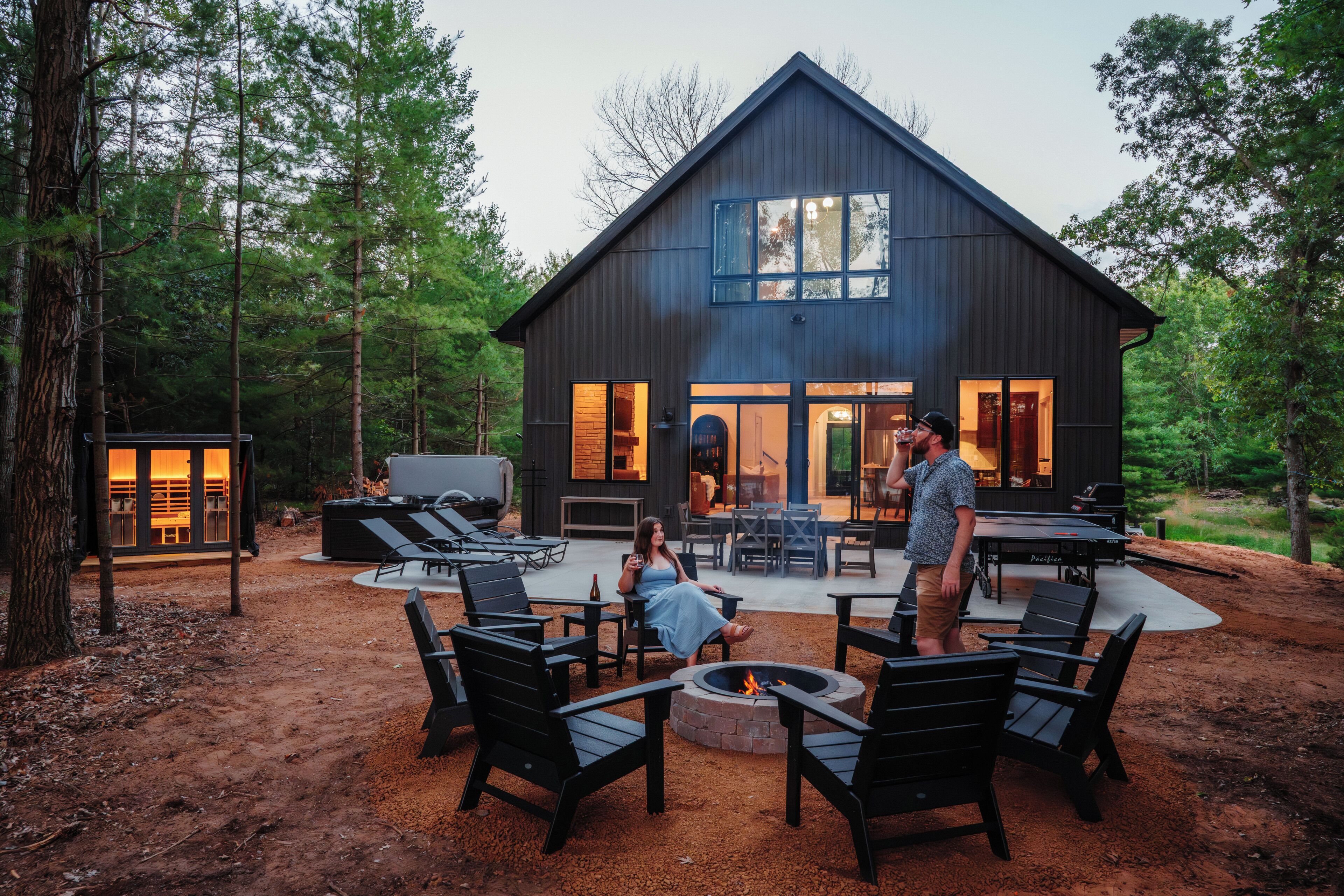 Une maison moderne dotée d’un foyer extérieur, d’un espace salon extérieur et d’un coin barbecue.