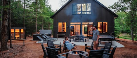 A modern house with a fire pit, outdoor seating, and a barbecue area.